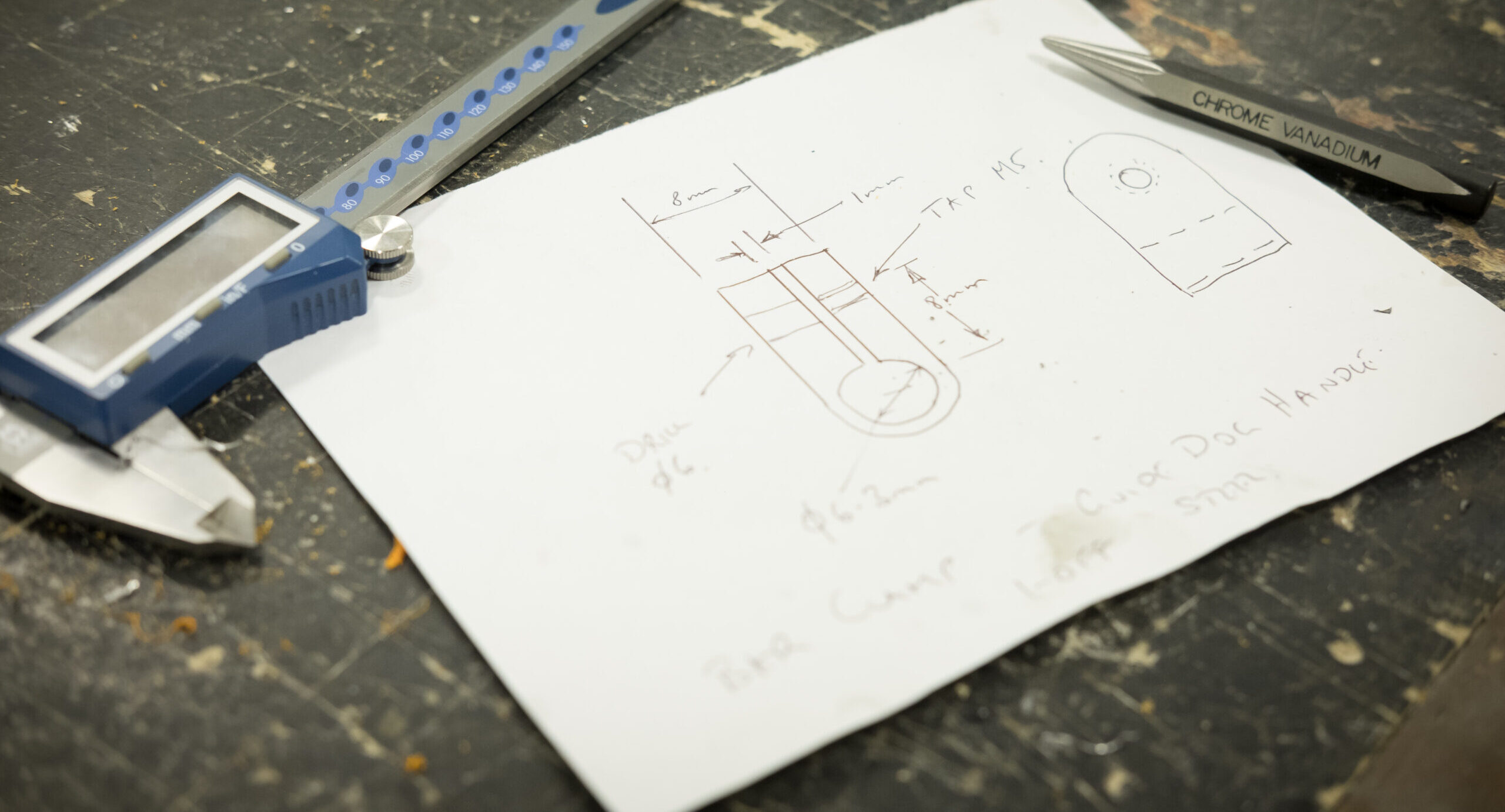 Piece of paper with sketches on next to a calliper.