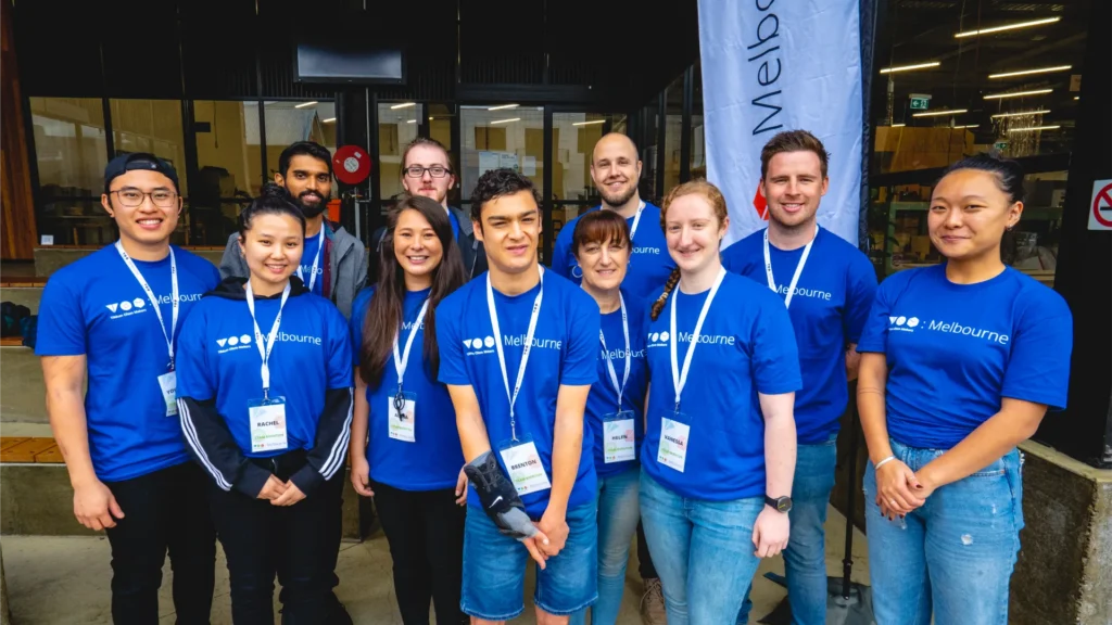 11 people in matching t-shirts posing for and smiling to the camera.