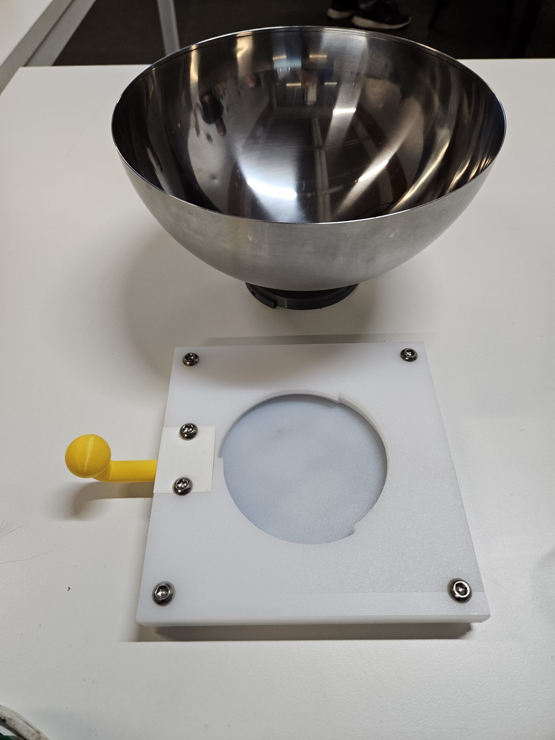 Stainless steel bowl next to a paper prototype of a bowl holder.