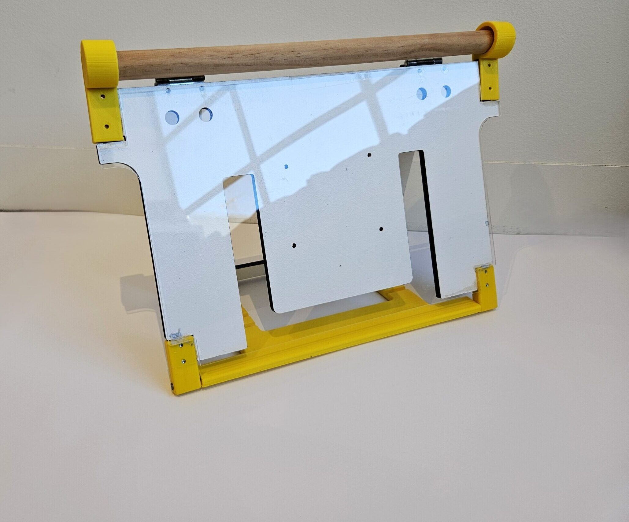 communication book stand prototype which is made from yellow 3d printed parts, a white panel and timber rod