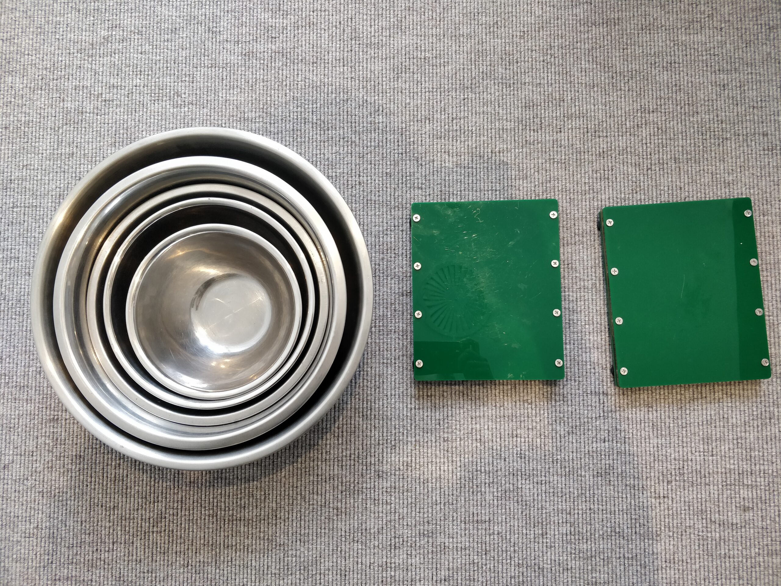 A range of stainless steel bowls next to two green magnetic boards.