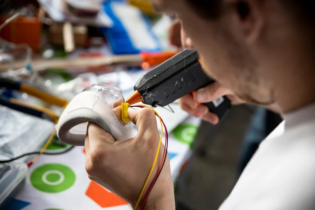 Person using hot glue gun on a prototype.