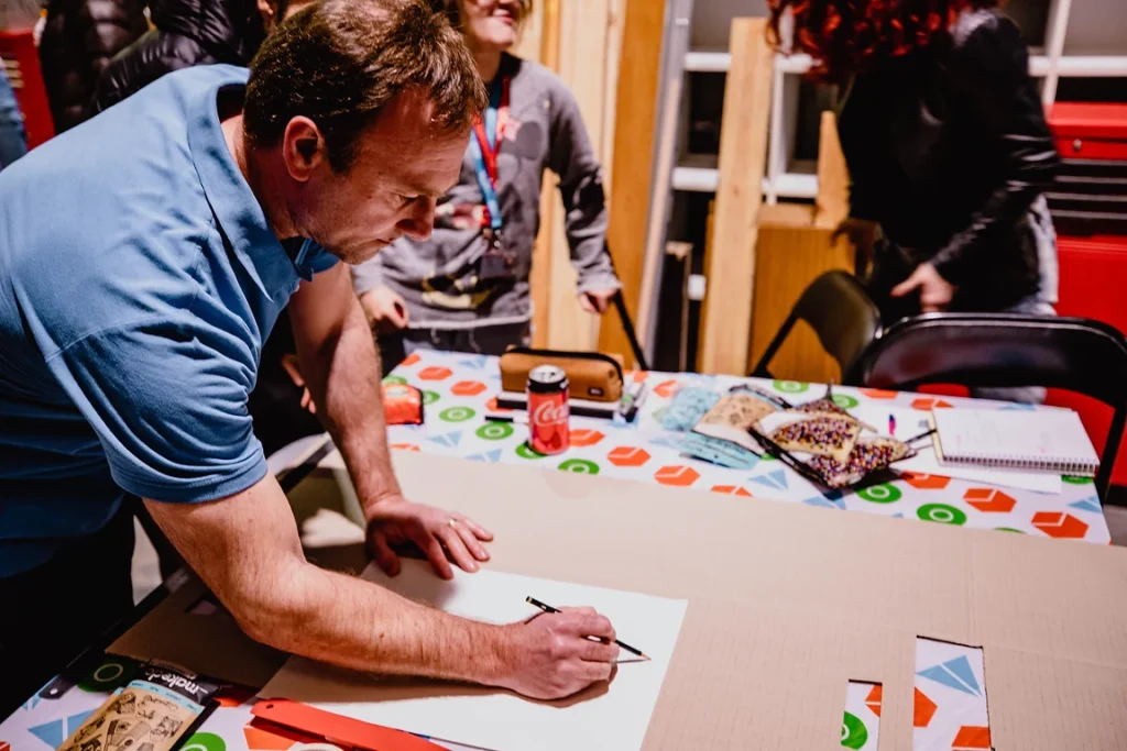 Man drawing with pencil on piece of cardboard.