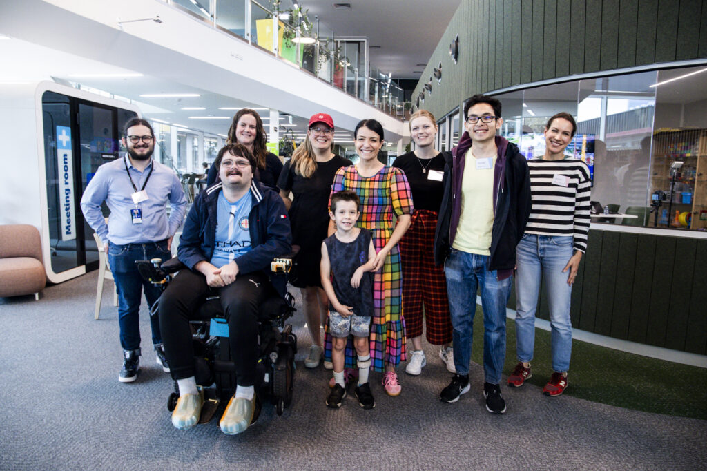 Nine people facing the camera in two rows are smiling.