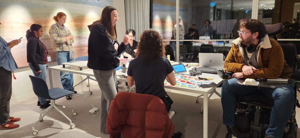 People are standing and sitting around a conference table.