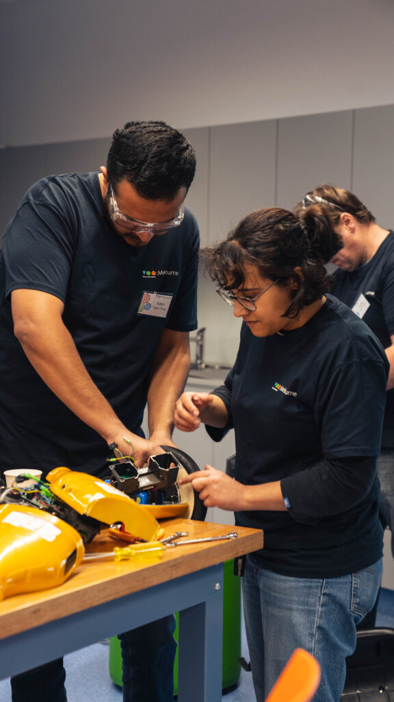 Two people in tom t-shirts are working with their hands on a prototype.