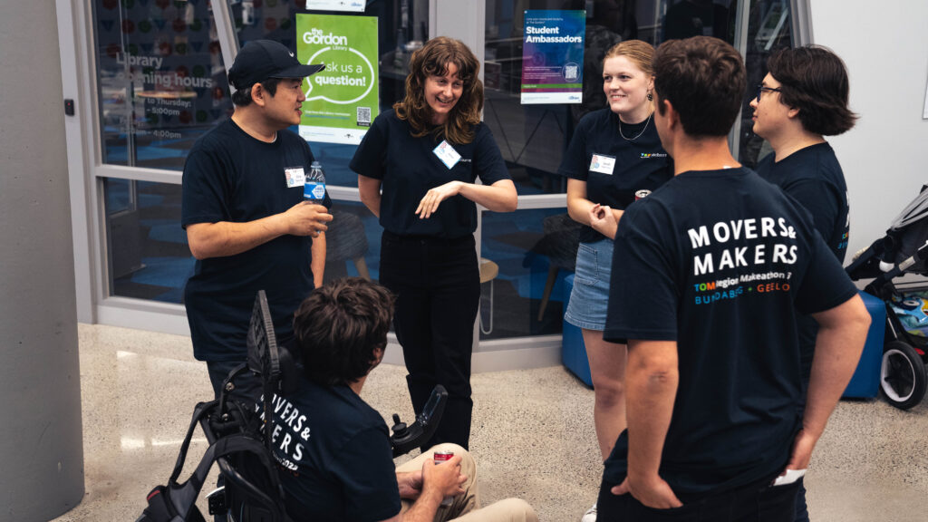 Six people standing in a ring talking and smiling.