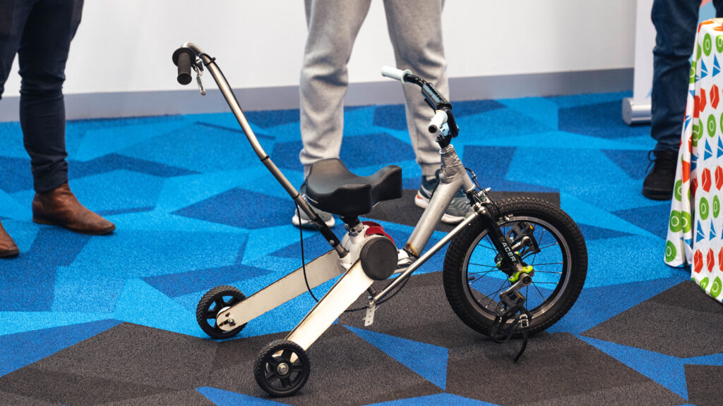 Modified kids bike with a handle and support wheels at the back.