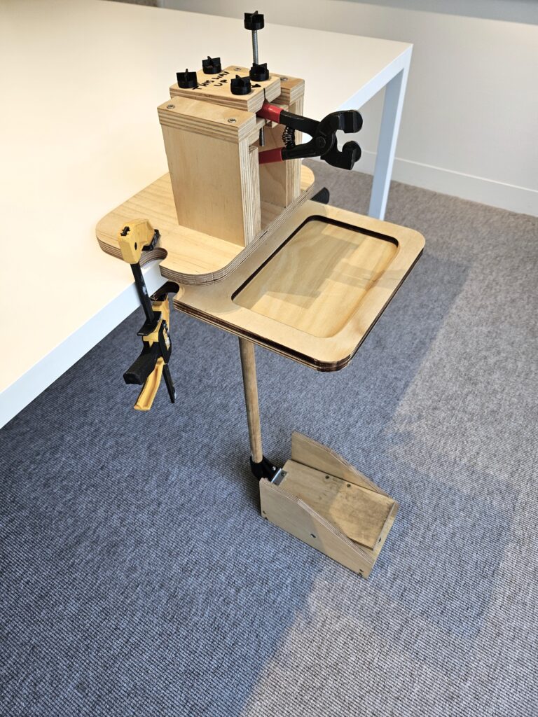 Glass cutter prototype made out of wood with tong and a foot pedal.