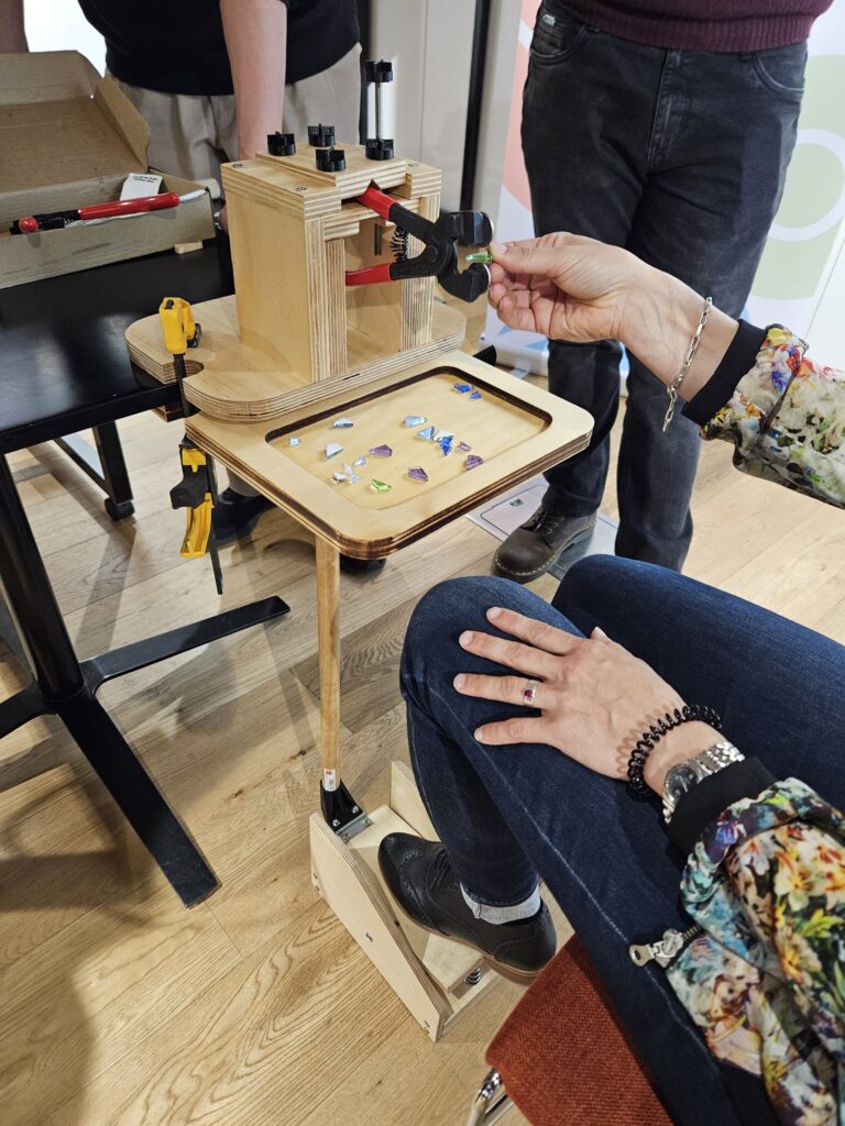 Person using a glass cutter prototype to cut mosaic glass pieces with a foot pedal.
