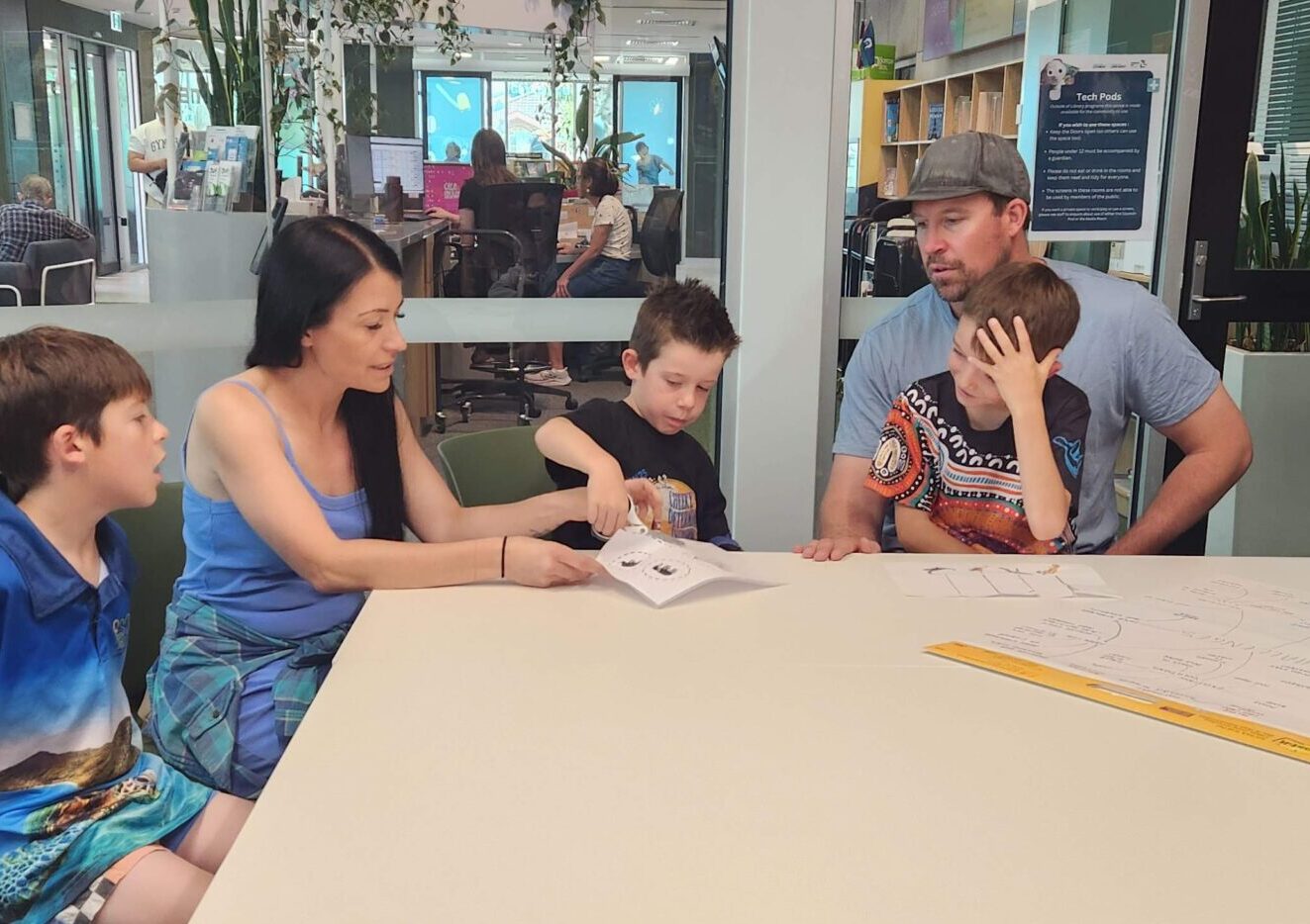 People sitting around a conference table watching a boy using scissors.