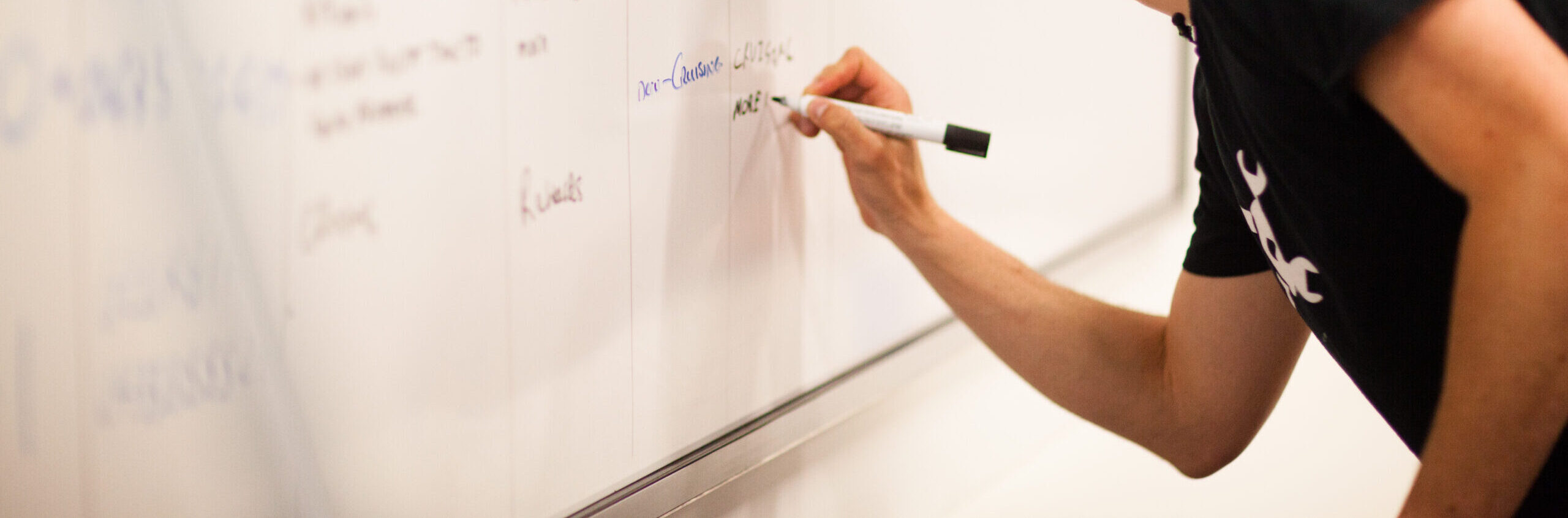 Man writing notes on a white board.