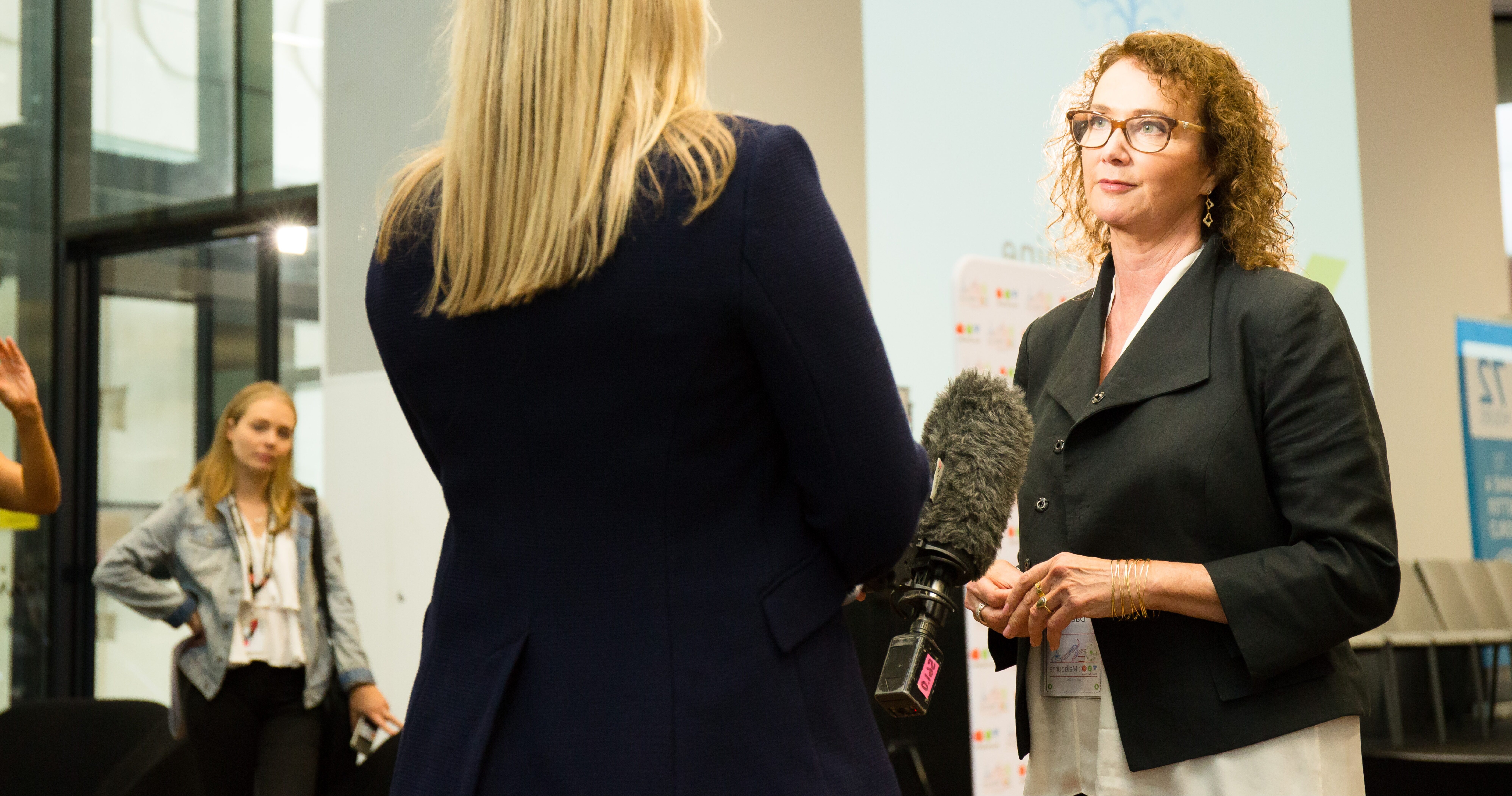 Woman in suit being interviewed by another woman with a microphone.