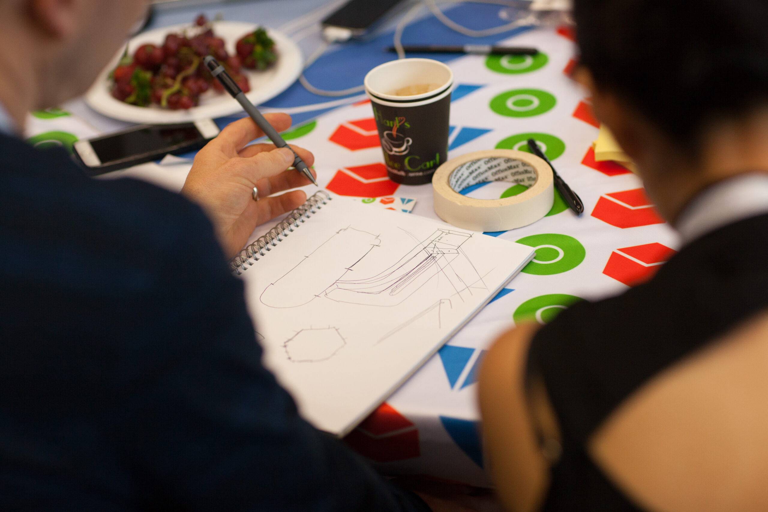 People from behind sketching concepts with pen and paper.