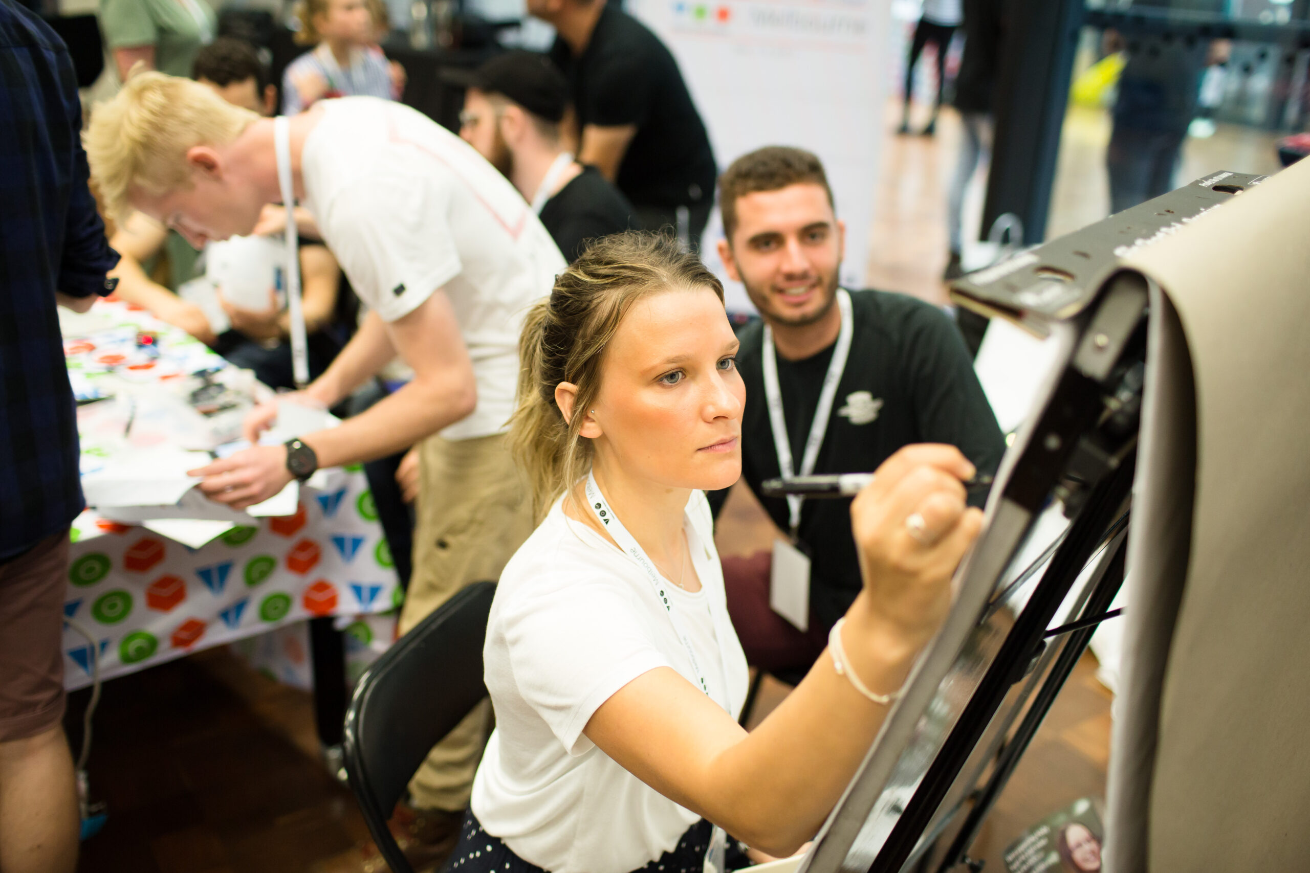 Woman is writing on a whiteboard while others watch.