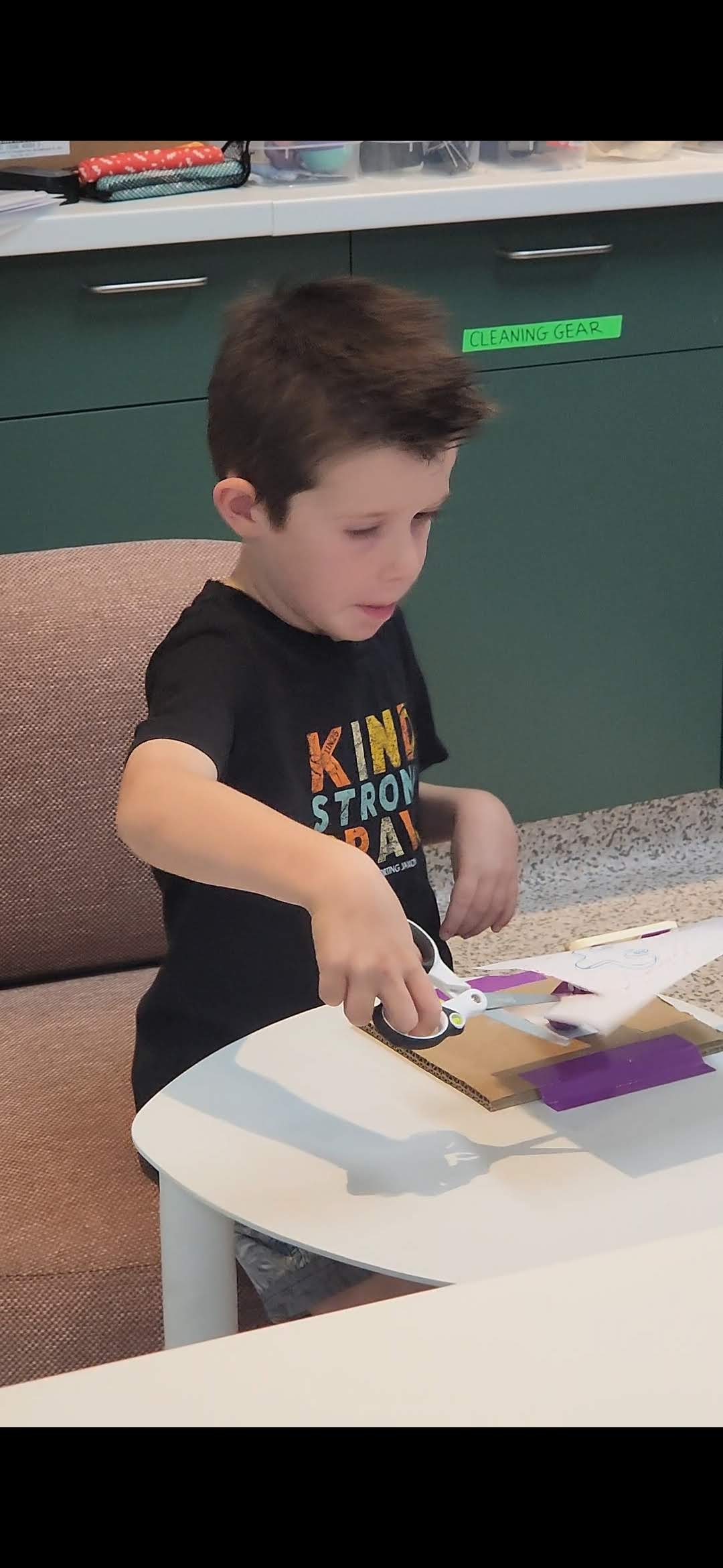 Young boy cutting paper with scissors.
