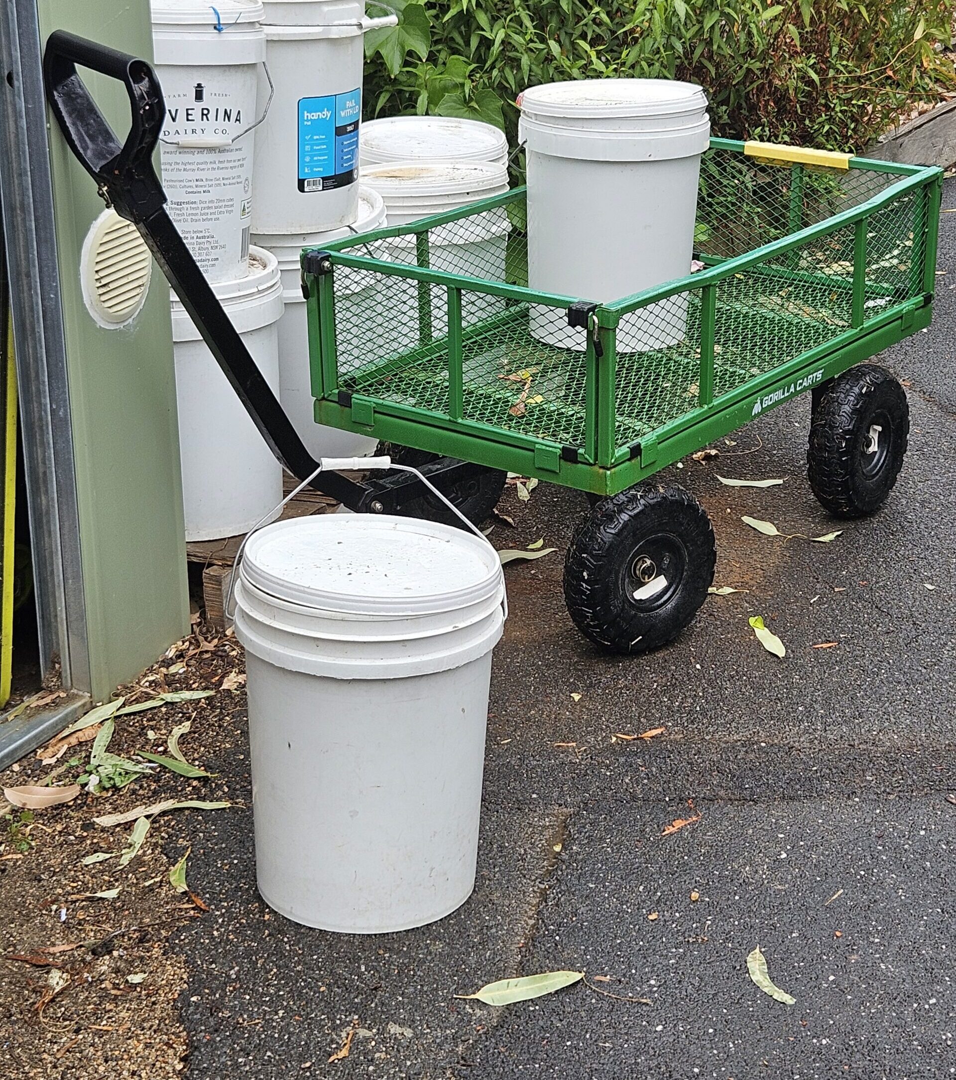 group of white compost buckets and a trolley in a garden setting