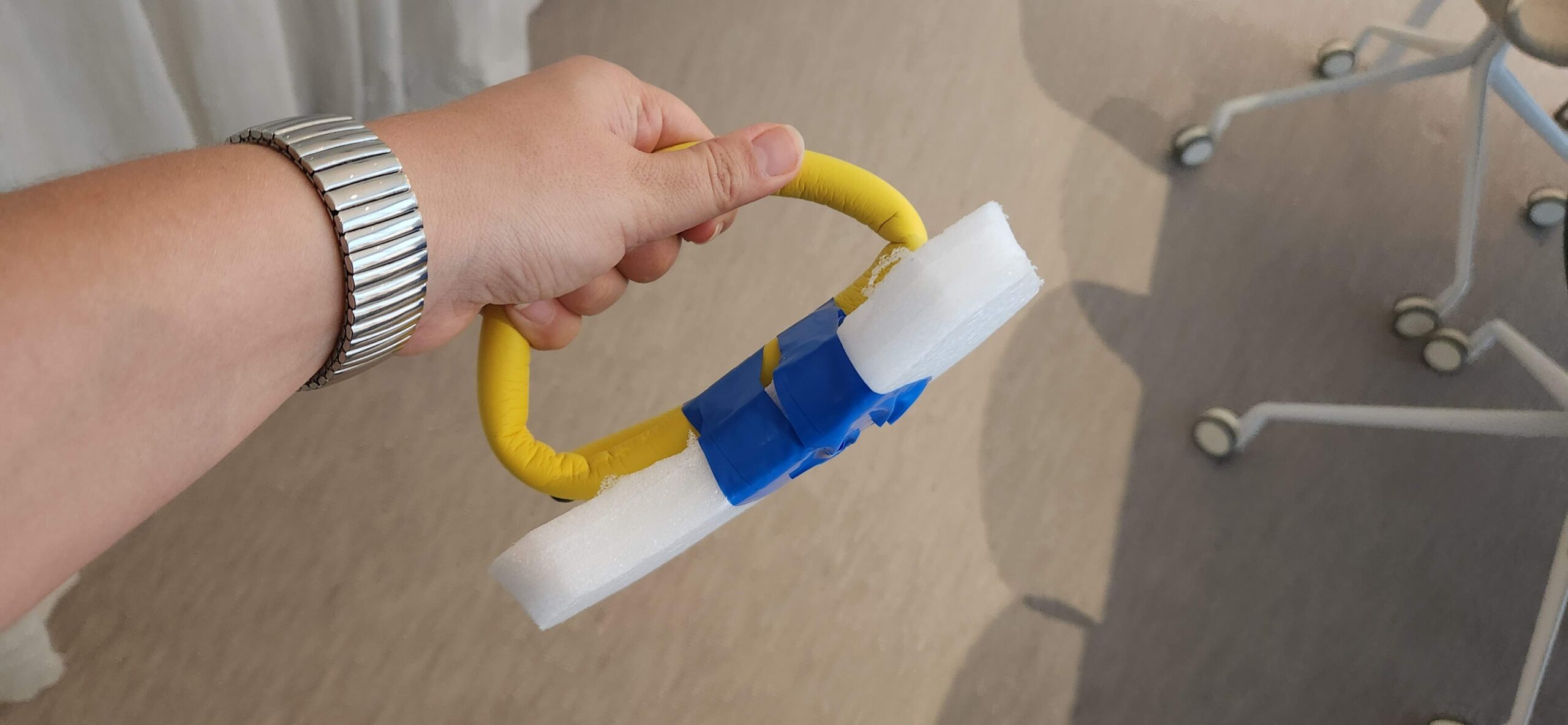 Hand holding a yellow foam handle attached to a block of foam.