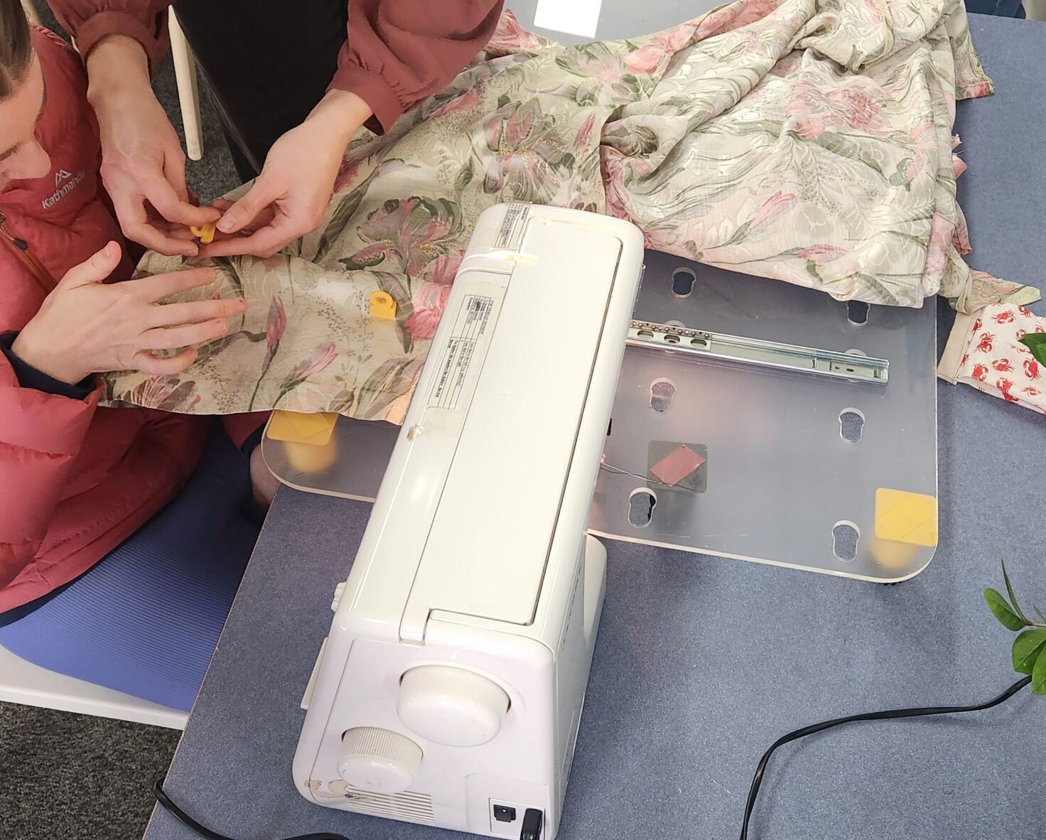 Two women setting up a sewing machine extension table.