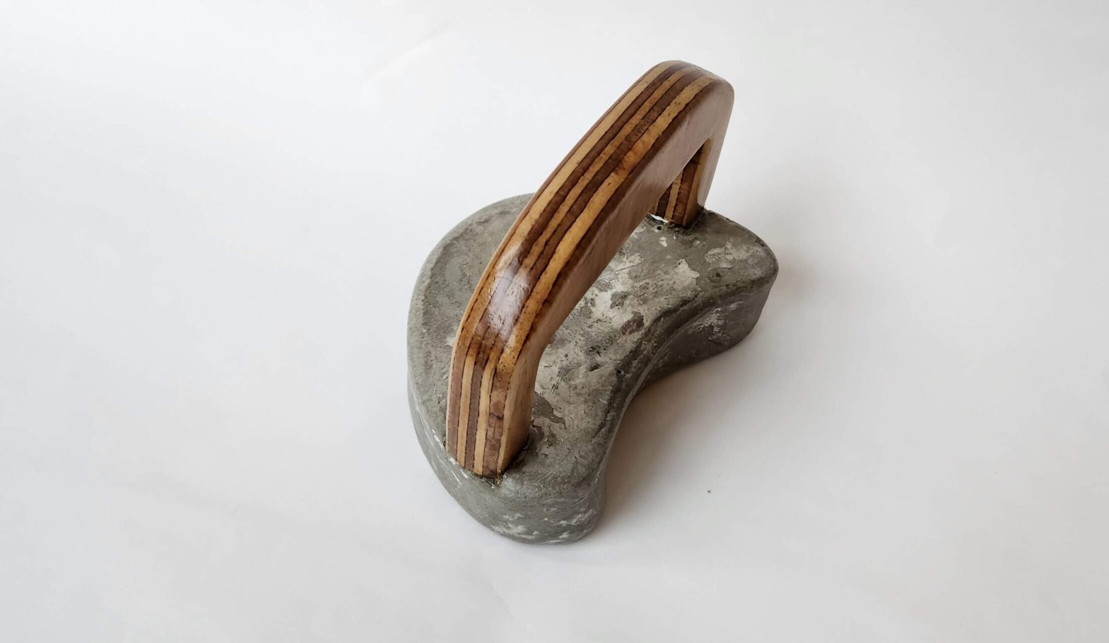 A moon shaped concrete block with a wooden handle.