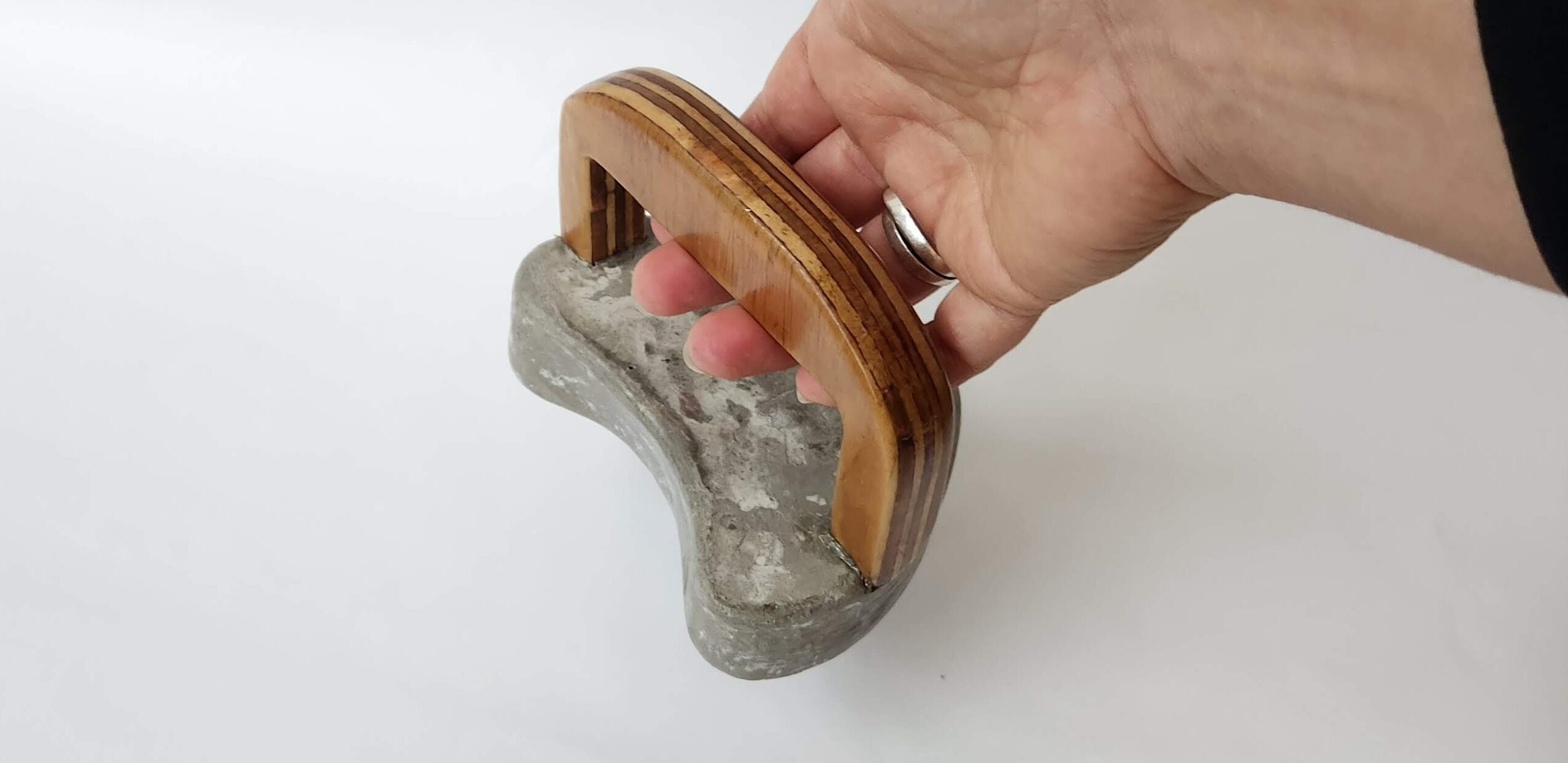 Hand holding a concrete block with wooden handle.