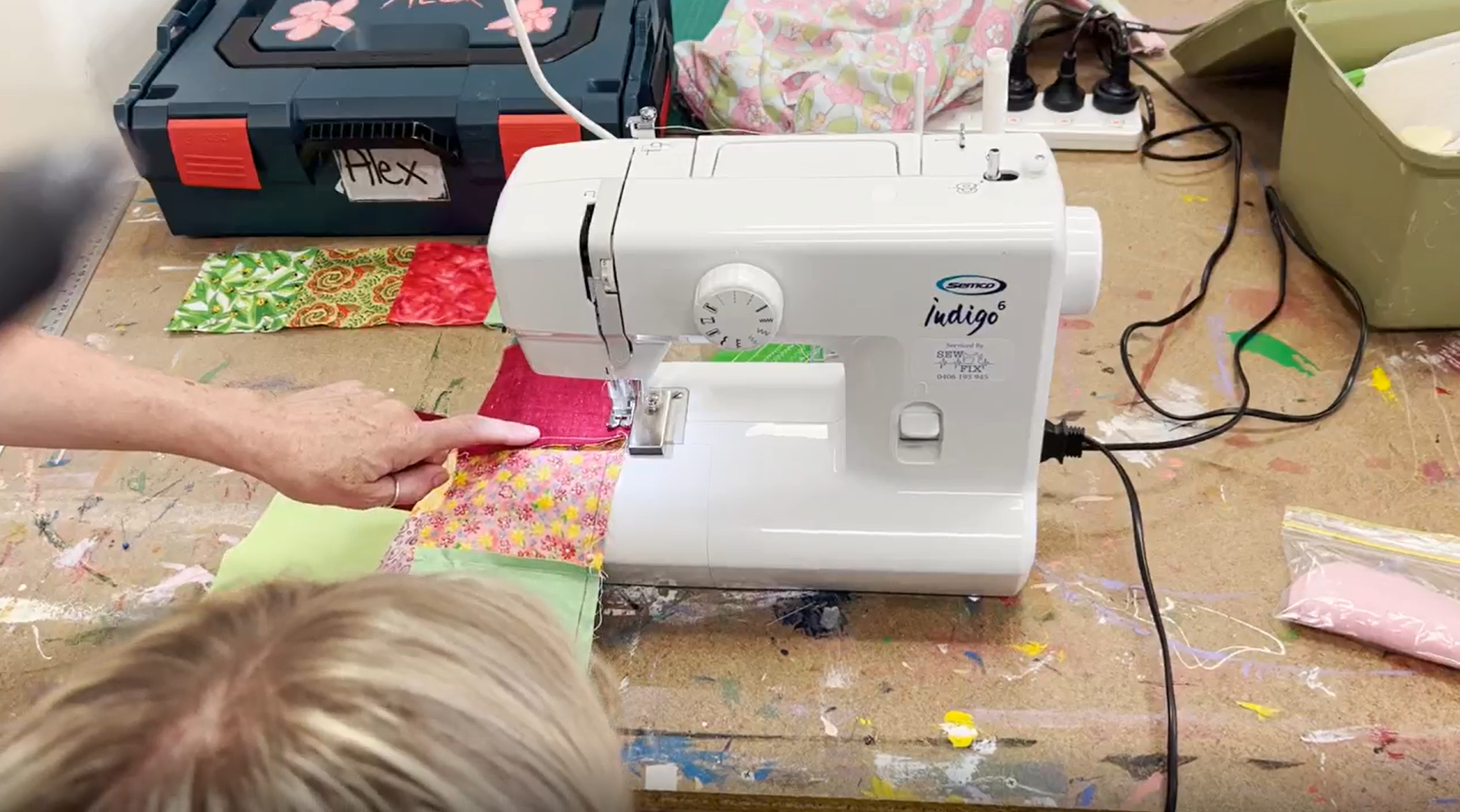 Sewing machine being used by two people out of frame.