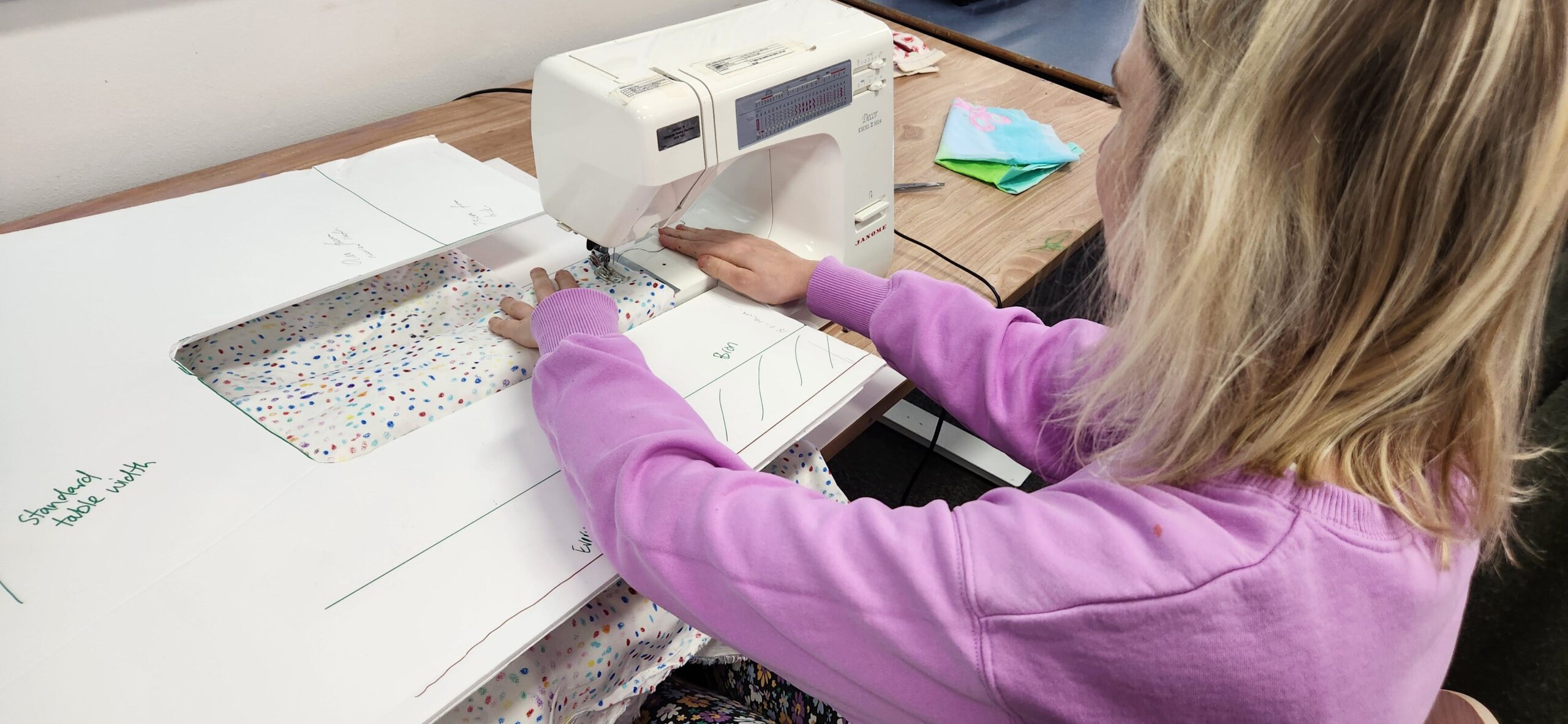 Woman from behind testing a paper prototype for a sewing machine.