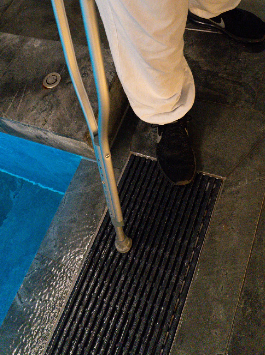 Close up of person walking with crutches over pool grate