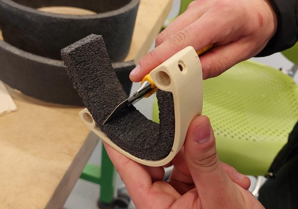 Hands holding cutting foam panel to fit a 3d printed part.