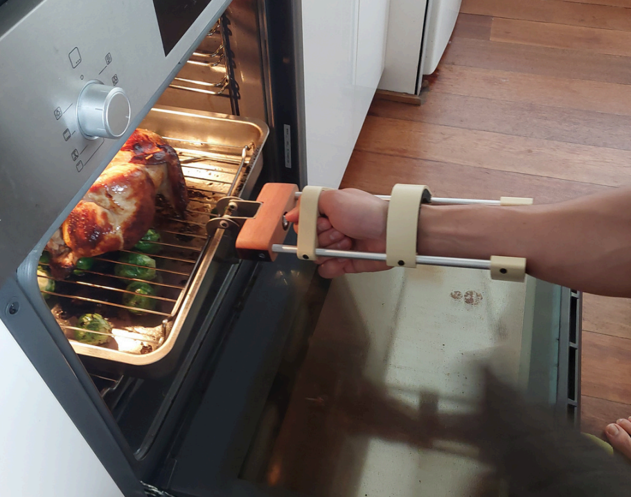 Person pulling a chicken and veggies out of an oven.