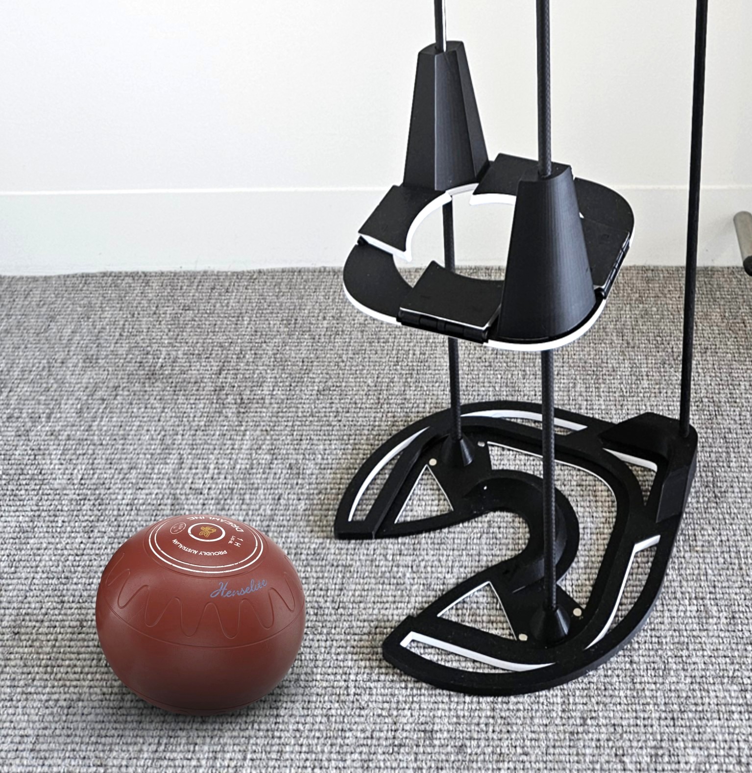 close up view of the base of the powered bowls lifter with a dark red bowl on the floor beside it