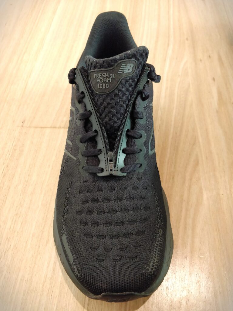 Black shoe with the shoelace insert laced into the laces. The zipper is shown in the un-done position