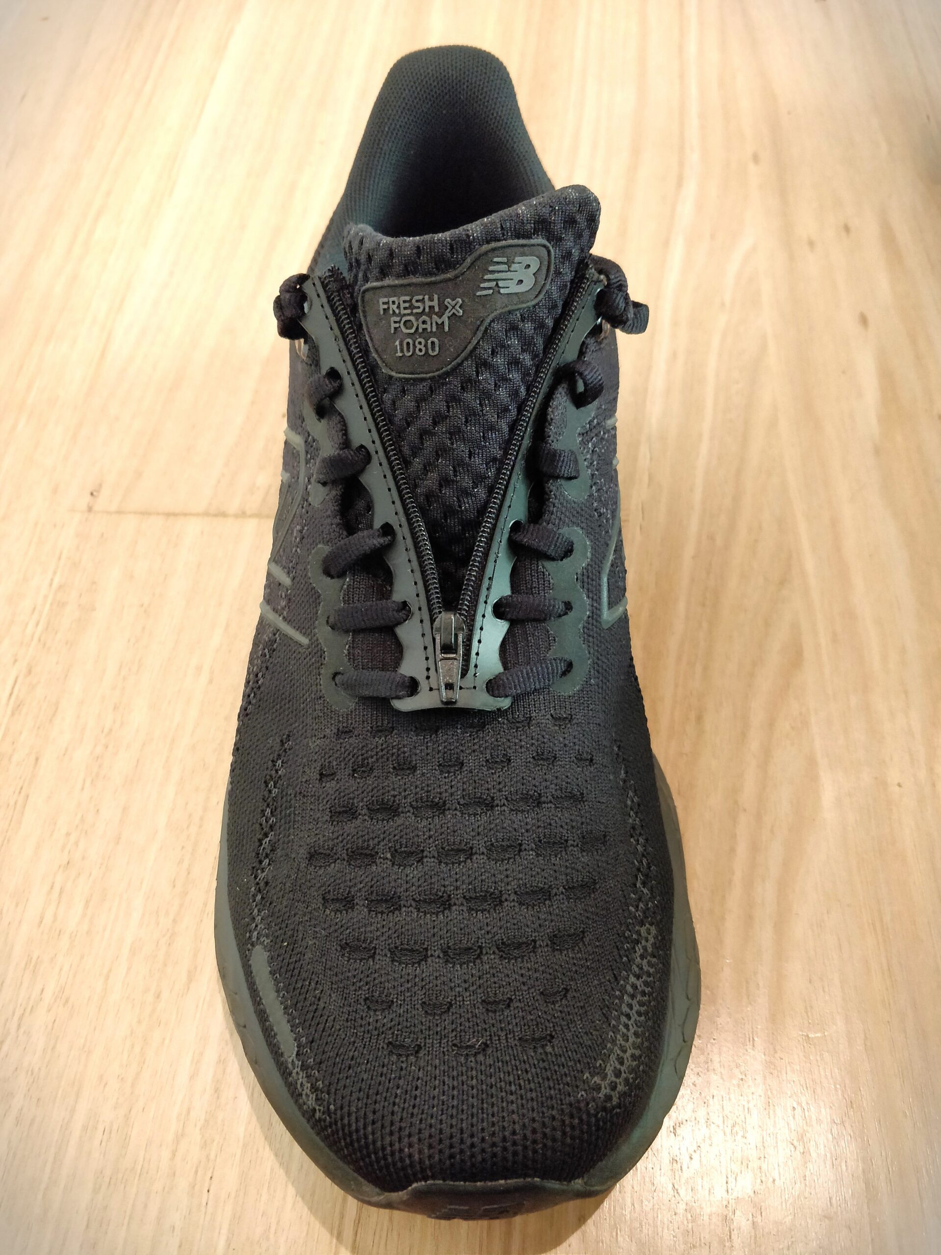 Black shoe with the shoelace insert laced into the laces. The zipper is shown in the un-done position